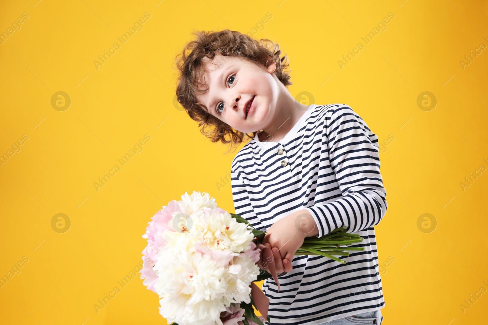 Cute little boy with bouquet of beautiful peonies on yellow background Photo of Cute little boy with bouquet of beautiful peonies on yellow background