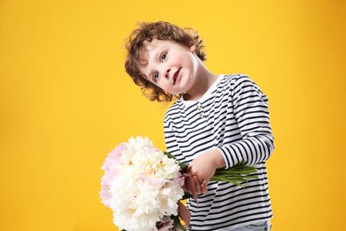 Photo of Cute little boy with bouquet of beautiful peonies on yellow background