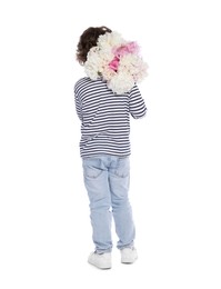 Photo of Cute little boy with bouquet of beautiful peonies on white background, back view