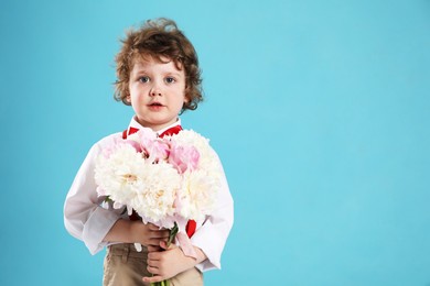 Photo of Cute little boy with bouquet of beautiful peonies on light blue background. Space for text