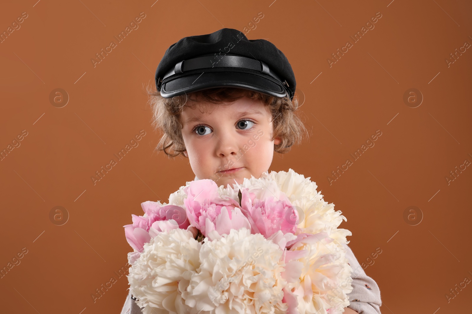 Cute little boy with bouquet of beautiful peonies on brown background Photo of Cute little boy with bouquet of beautiful peonies on brown background