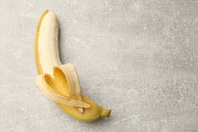 Photo of Banana with heart made of peel on grey table, top view. Space for text