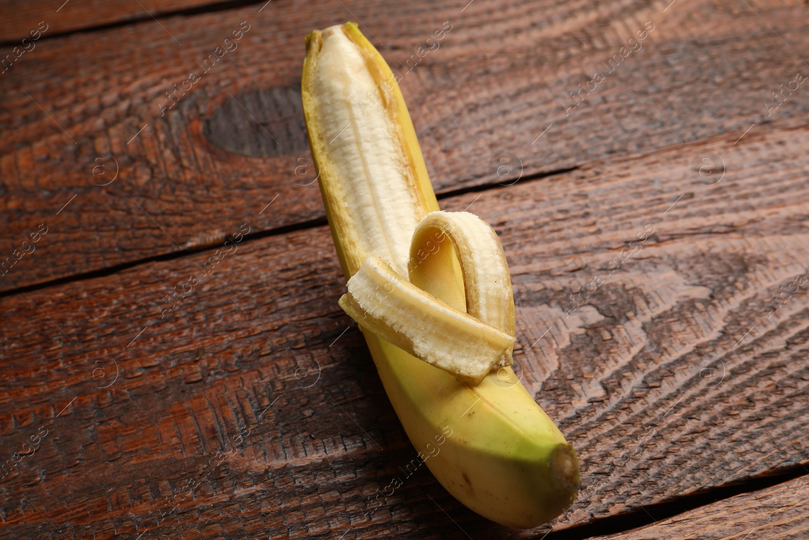 Banana with heart made of peel on wooden table, above view Photo of Banana with heart made of peel on wooden table, above view