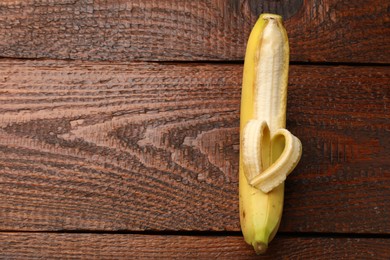 Photo of Banana with heart made of peel on wooden table, top view. Space for text