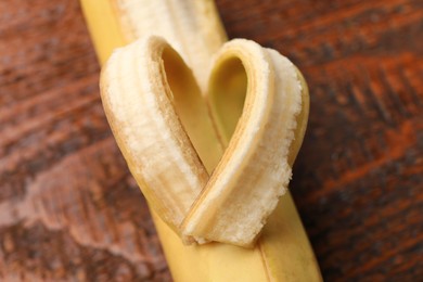 Photo of Banana with heart made of peel on wooden table, above view