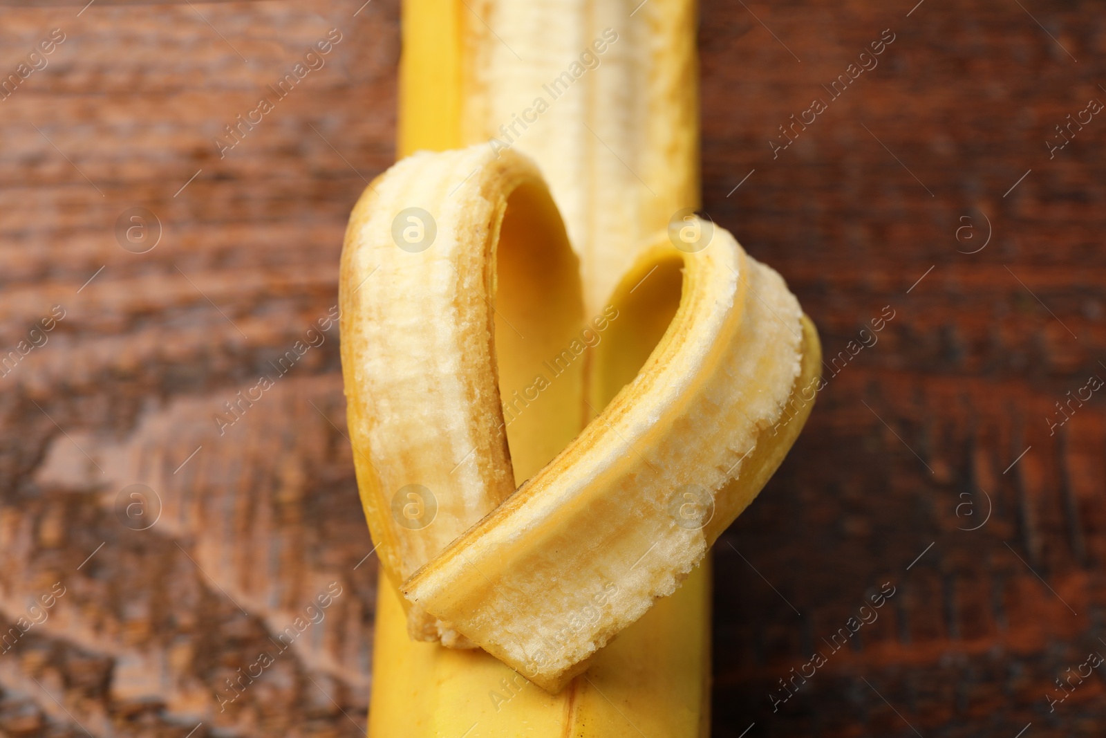 Banana with heart made of peel on wooden table, above view Photo of Banana with heart made of peel on wooden table, above view