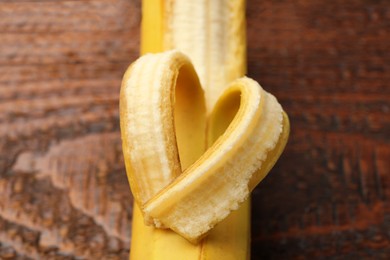 Photo of Banana with heart made of peel on wooden table, above view