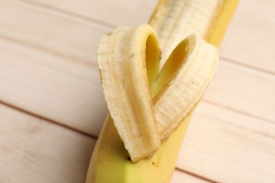 Photo of Banana with heart made of peel on wooden table, above view