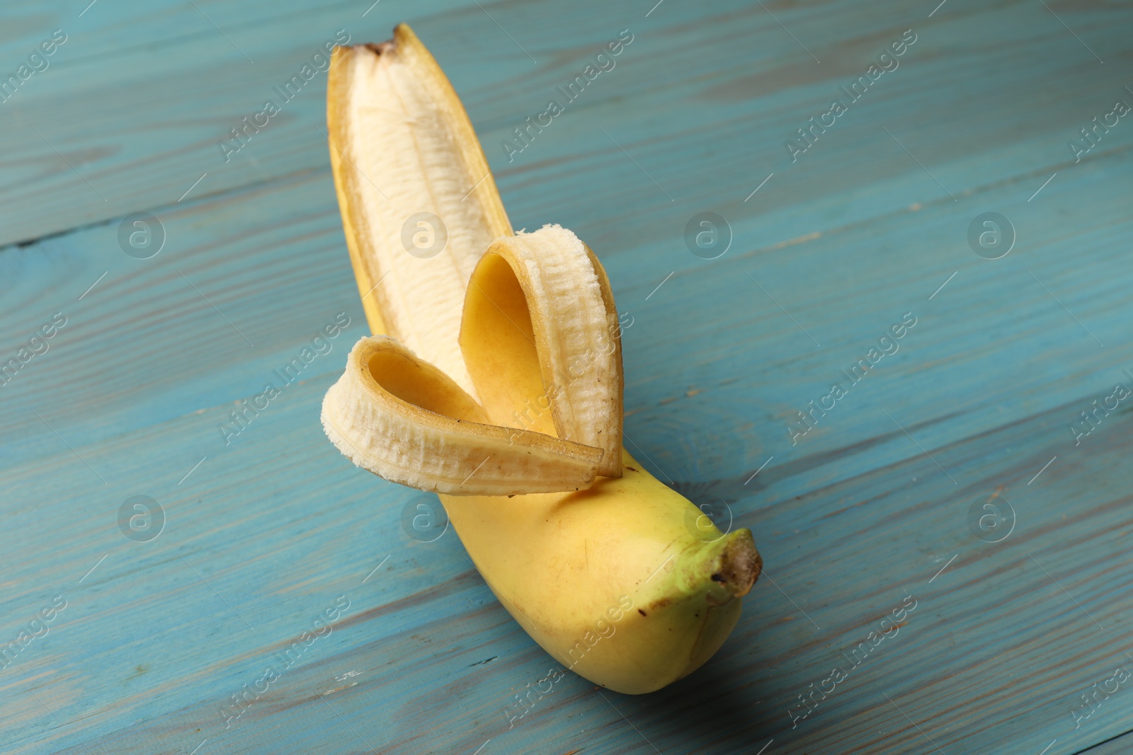 Banana with heart made of peel on light blue wooden table, closeup Photo of Banana with heart made of peel on light blue wooden table, closeup
