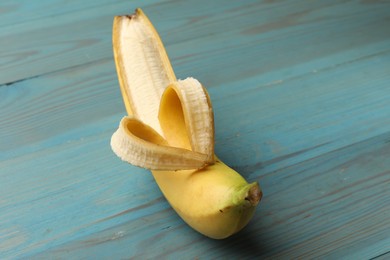 Photo of Banana with heart made of peel on light blue wooden table, closeup