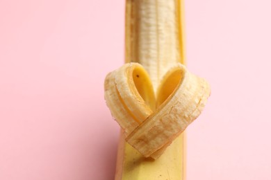 Photo of Banana with heart made of peel on pink background, closeup. Space for text
