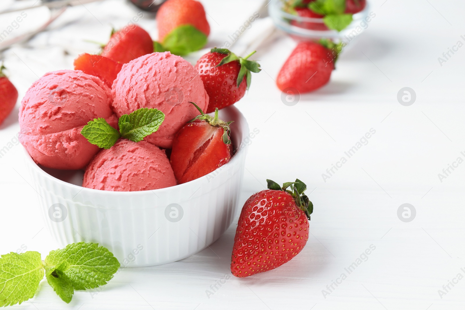 Photo of Tasty sorbet with strawberries and mint served on white wooden table, closeup. Space for text