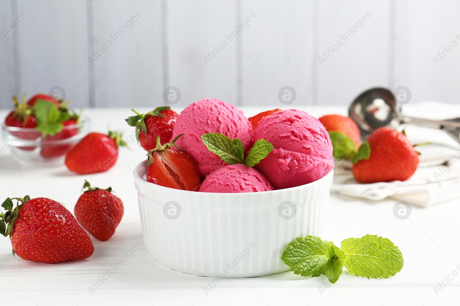 Photo of Tasty sorbet with strawberries and mint served on white wooden table, closeup