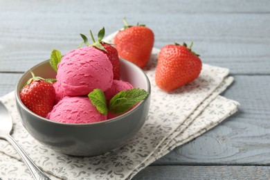 Photo of Tasty sorbet with strawberries and mint served on grey wooden table, closeup