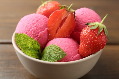 Photo of Tasty sorbet with strawberries and mint served on wooden table, closeup