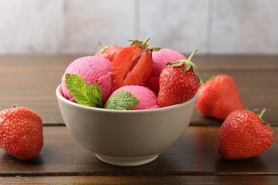Photo of Tasty sorbet with strawberries and mint served on wooden table, closeup