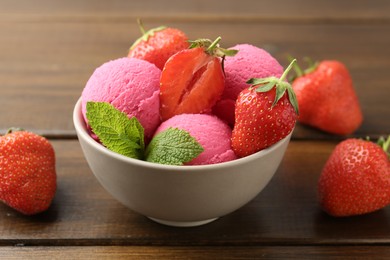 Photo of Tasty sorbet with strawberries and mint served on wooden table, closeup