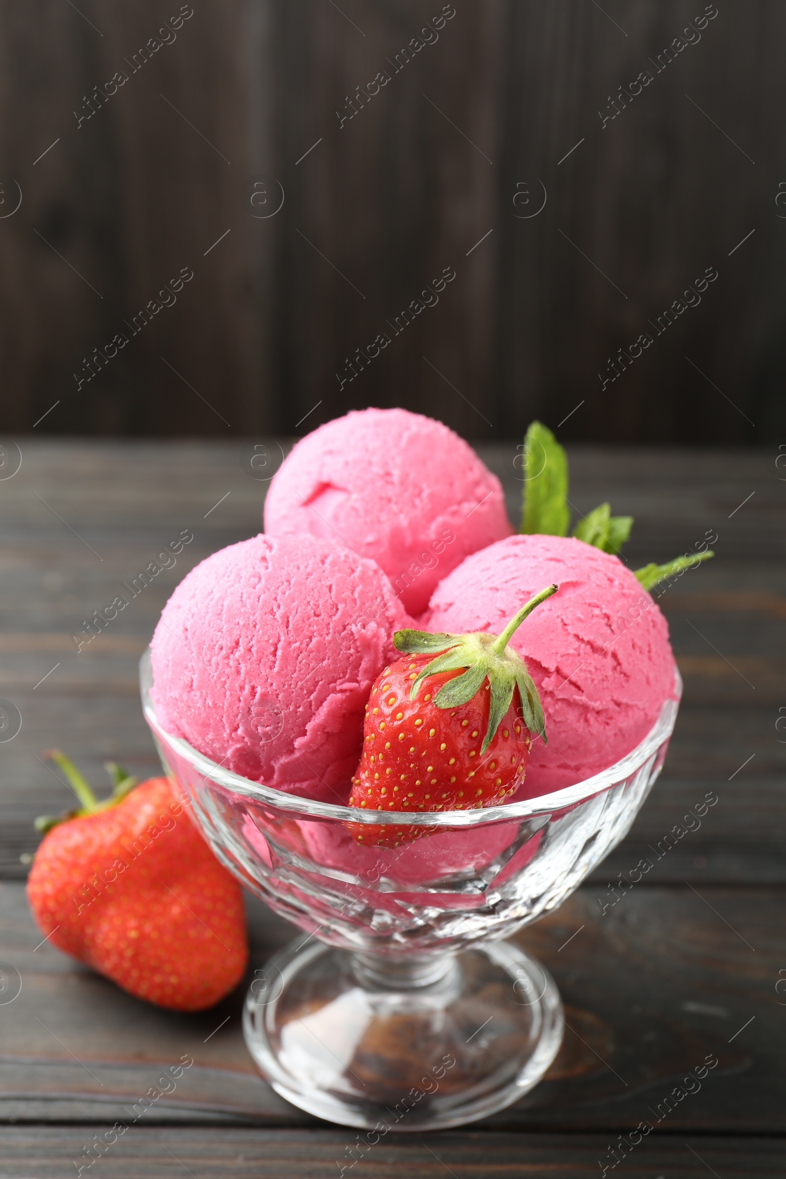 Tasty sorbet with strawberries and mint served on wooden table, closeup Photo of Tasty sorbet with strawberries and mint served on wooden table, closeup