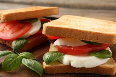 Photo of Tasty sandwiches with mozzarella cheese, tomatoes and basil on table, closeup