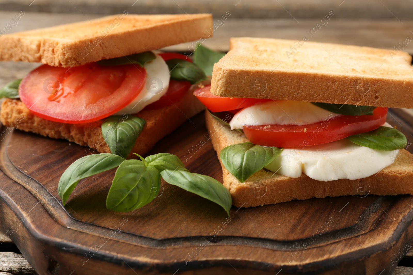 Tasty sandwiches with mozzarella cheese, tomatoes and basil on table, closeup Photo of Tasty sandwiches with mozzarella cheese, tomatoes and basil on table, closeup