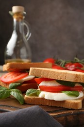 Photo of Tasty sandwiches with mozzarella cheese, tomatoes and basil on table, closeup