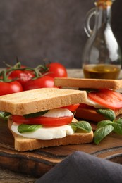 Photo of Tasty sandwiches with mozzarella cheese, tomatoes and basil on table, closeup
