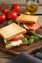 Photo of Tasty sandwiches with mozzarella cheese, tomatoes and basil on wooden table, closeup