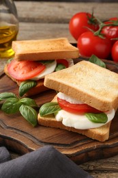 Photo of Tasty sandwiches with mozzarella cheese, tomatoes and basil on table, closeup