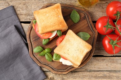 Photo of Tasty sandwiches with mozzarella cheese, tomatoes and basil on wooden table, flat lay