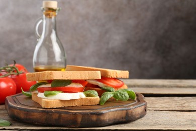 Photo of Tasty sandwiches with mozzarella cheese, tomatoes and basil on wooden table, closeup. Space for text