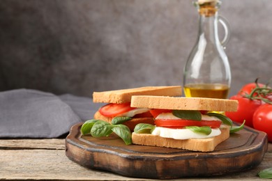 Photo of Tasty sandwiches with mozzarella cheese, tomatoes and basil on wooden table, closeup. Space for text
