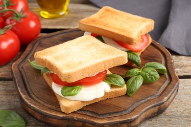 Photo of Tasty sandwiches with mozzarella cheese, tomatoes and basil on wooden table, closeup