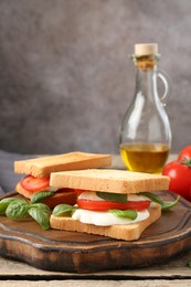 Photo of Tasty sandwiches with mozzarella cheese, tomatoes and basil on wooden table, closeup