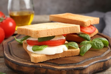 Photo of Tasty sandwiches with mozzarella cheese, tomatoes and basil on table, closeup