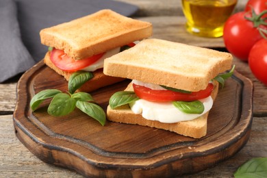Photo of Tasty sandwiches with mozzarella cheese, tomatoes and basil on wooden table, closeup