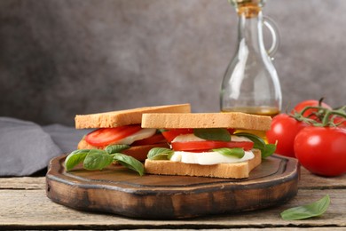 Photo of Tasty sandwiches with mozzarella cheese, tomatoes and basil on wooden table, closeup