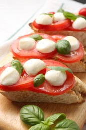 Photo of Tasty sandwiches with mozzarella cheese, tomatoes and basil on table, closeup