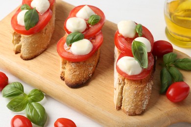 Photo of Tasty sandwiches with mozzarella cheese, tomatoes and basil on white table, above view