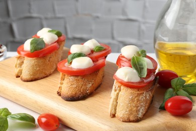 Photo of Tasty sandwiches with mozzarella cheese, tomatoes and basil on white table, closeup