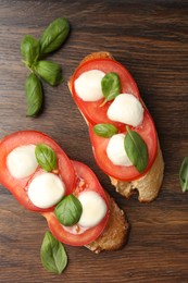 Photo of Tasty sandwiches with mozzarella cheese, tomatoes and basil on wooden table, flat lay