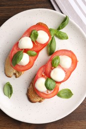 Photo of Tasty sandwiches with mozzarella cheese, tomatoes and basil on wooden table, top view