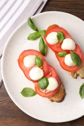Photo of Tasty sandwiches with mozzarella cheese, tomatoes and basil on wooden table, top view