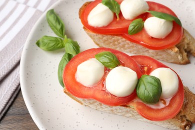 Photo of Tasty sandwiches with mozzarella cheese, tomatoes and basil on table, above view