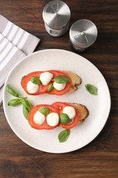 Photo of Tasty sandwiches with mozzarella cheese, tomatoes and basil on wooden table, flat lay