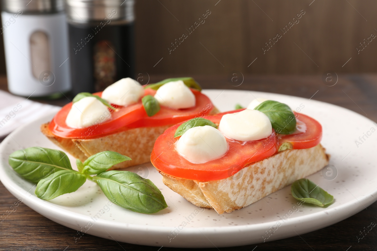 Tasty sandwiches with mozzarella cheese, tomatoes and basil on wooden table, closeup Photo of Tasty sandwiches with mozzarella cheese, tomatoes and basil on wooden table, closeup