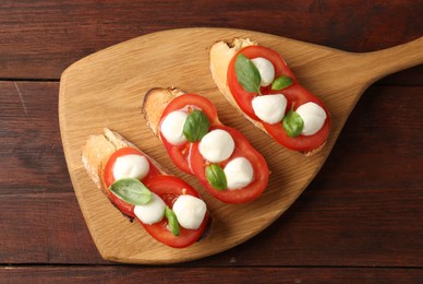 Photo of Tasty sandwiches with mozzarella cheese, tomatoes and basil on wooden table, top view