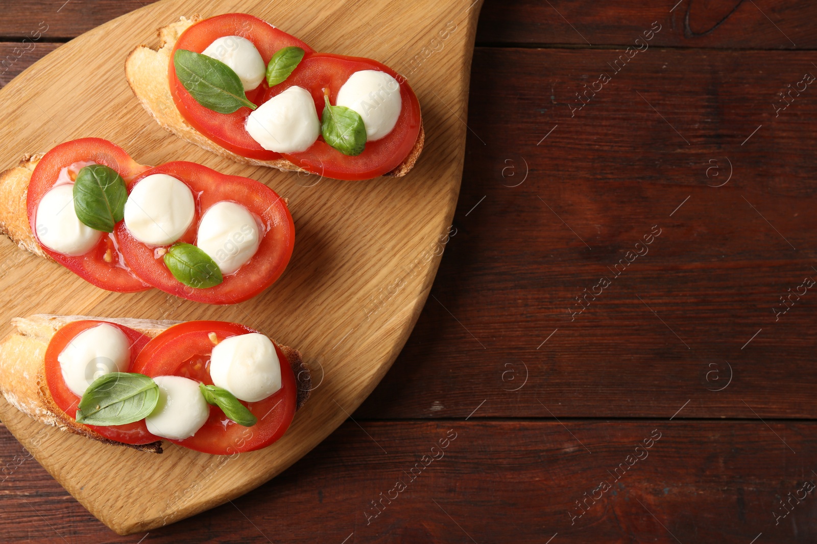 Tasty sandwiches with mozzarella cheese, tomatoes and basil on wooden table, top view. Space for text Photo of Tasty sandwiches with mozzarella cheese, tomatoes and basil on wooden table, top view. Space for text