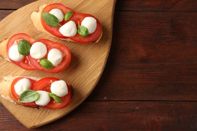 Photo of Tasty sandwiches with mozzarella cheese, tomatoes and basil on wooden table, top view. Space for text