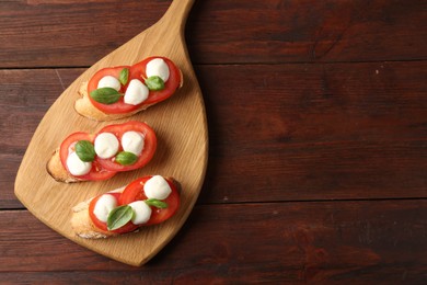 Photo of Tasty sandwiches with mozzarella cheese, tomatoes and basil on wooden table, top view. Space for text