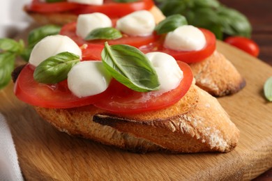 Photo of Tasty sandwiches with mozzarella cheese, tomatoes and basil on table, closeup